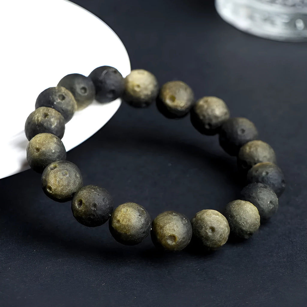 Natural obsidian crater ball bracelet with textured beads on a wrist, showing silver stone meteorite colour variant.
