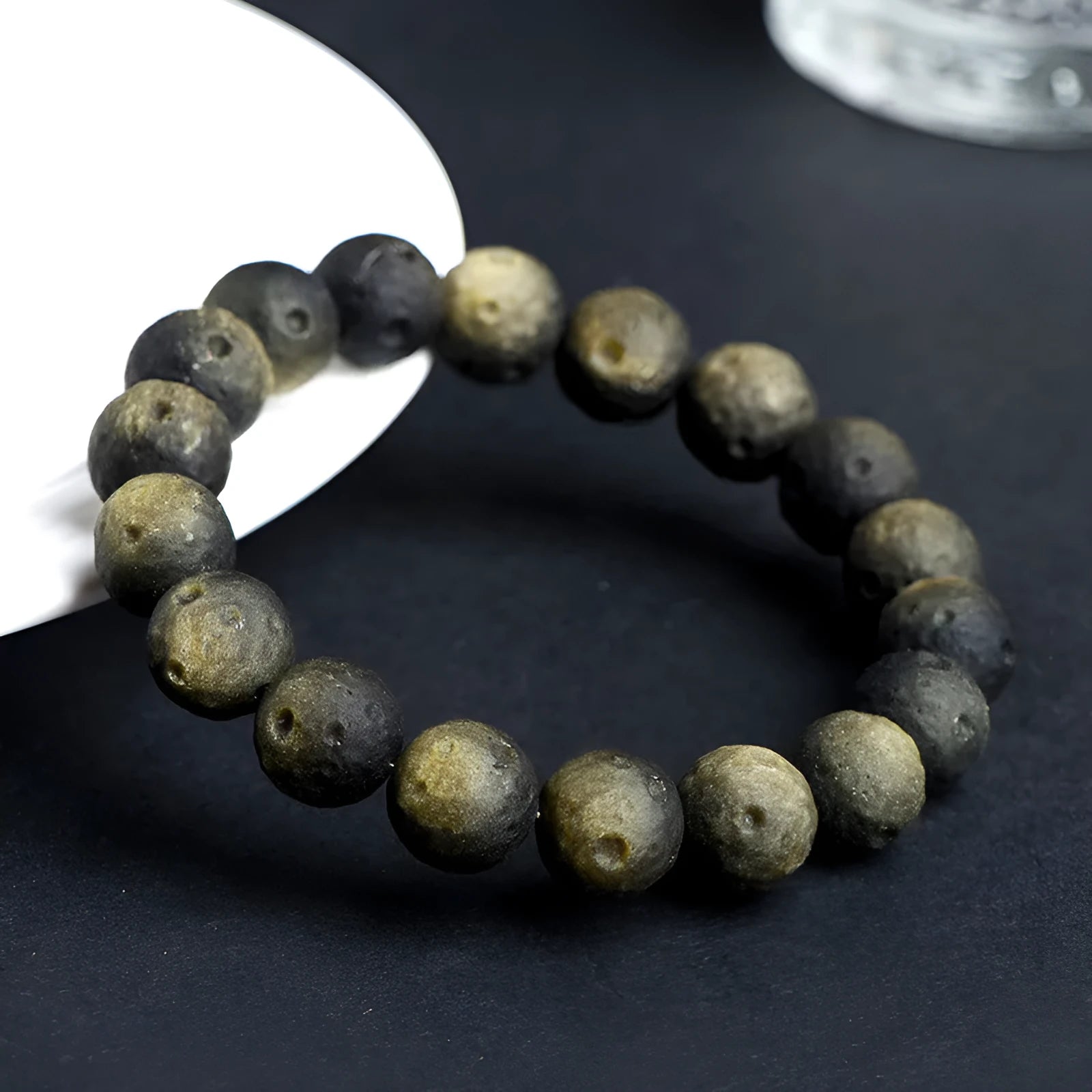 Natural obsidian crater ball bracelet with textured beads on a wrist, showing silver stone meteorite colour variant.