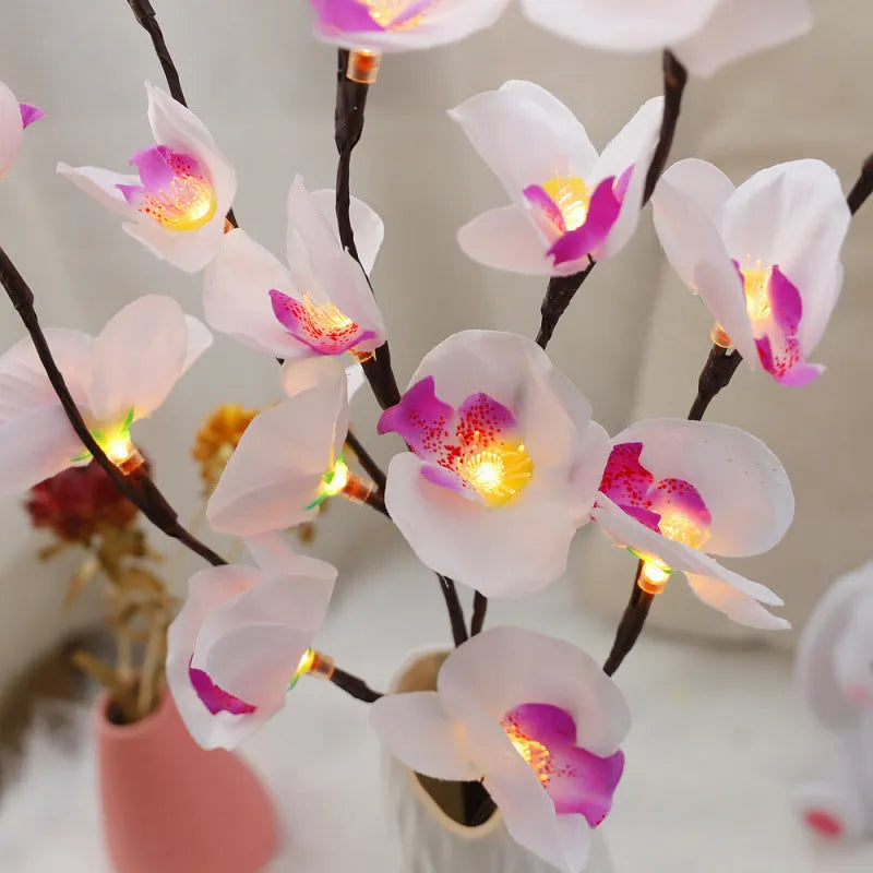 Pink LED phalaenopsis orchid branch decorative light on a table, 65 cm long with fabric leaves.