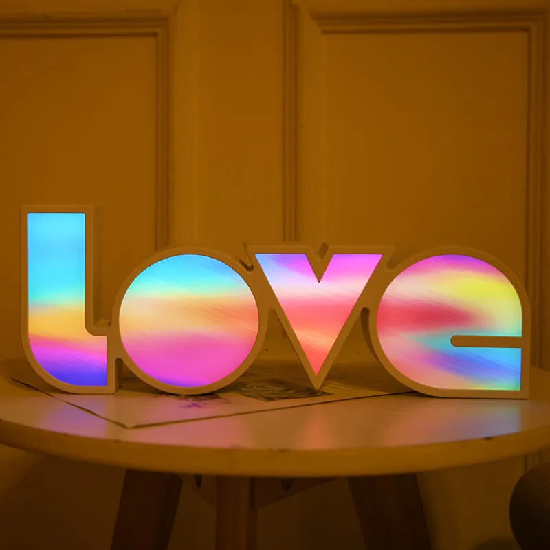 Colourful LED LOVE light decoration with rainbow lampshade on a table.