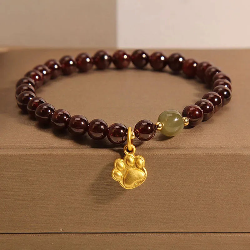 Women's adjustable crystal bracelet with a cat's paw shaped garnet stone centrepiece.