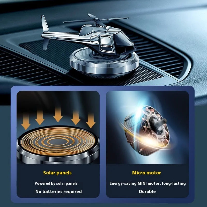 Silver solar-powered metal helicopter car air freshener with rotating blades on a dashboard.