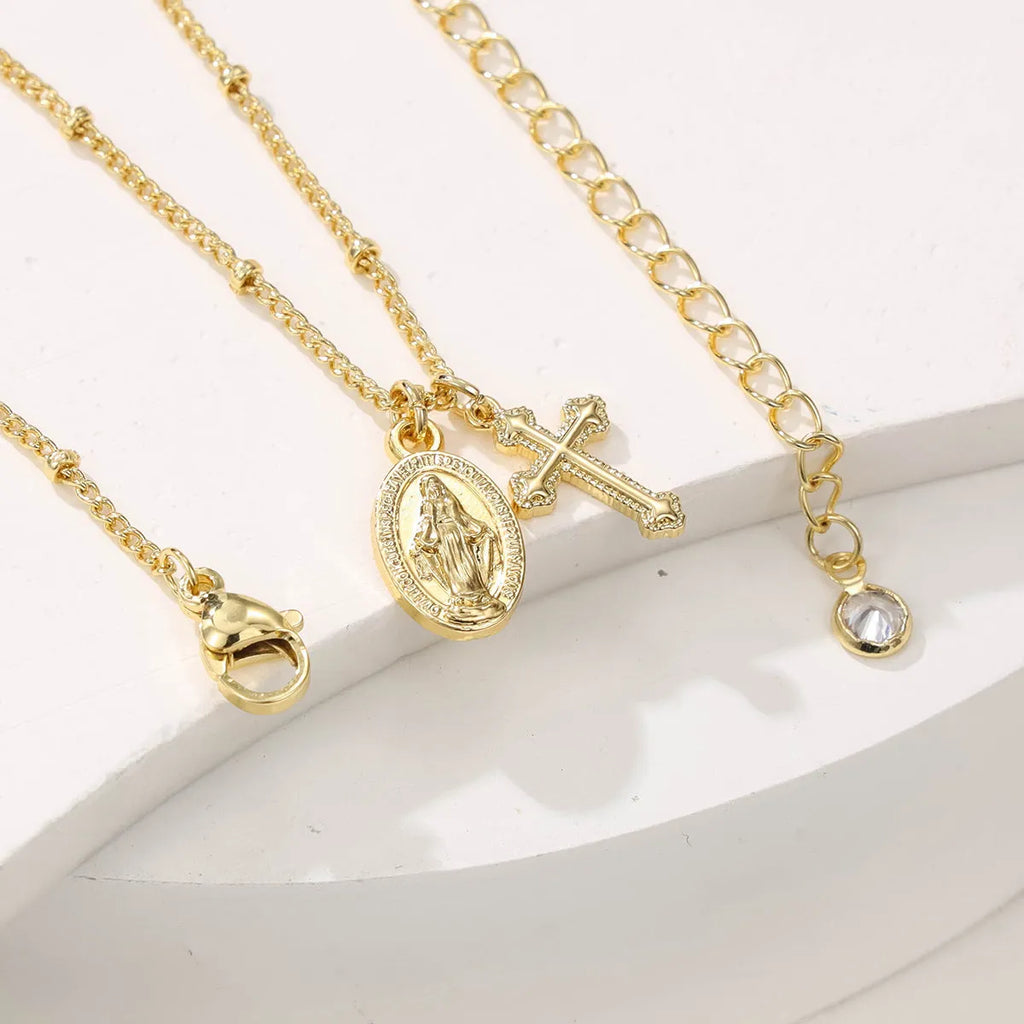 Gold geometric cross Virgin Mary pendant necklace on a chain.