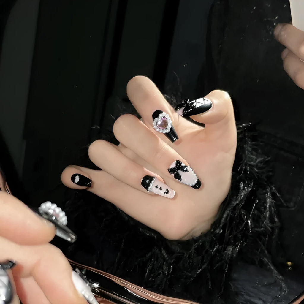 Handmade artificial nails with black and pink heart design and bow pattern in four sizes