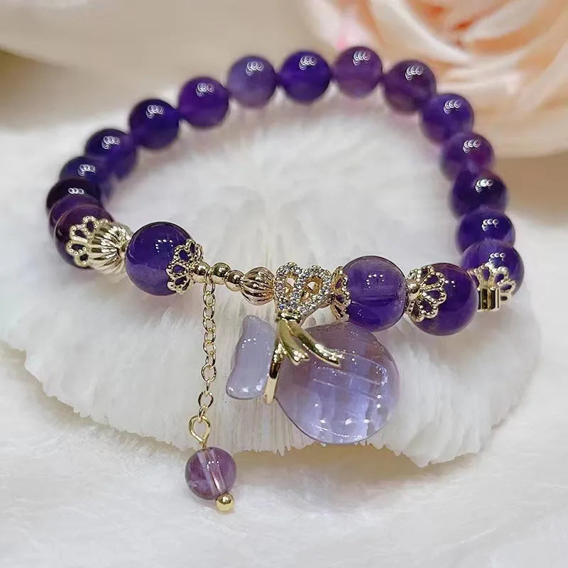 Purple amethyst bracelet with ethnic-style money bag pendant and geometric shapes on wrist