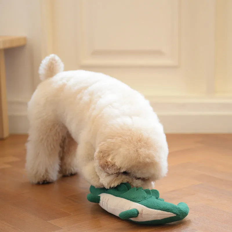 Green soft plush toy dog with floppy ears and embroidered face, lying on a white background.