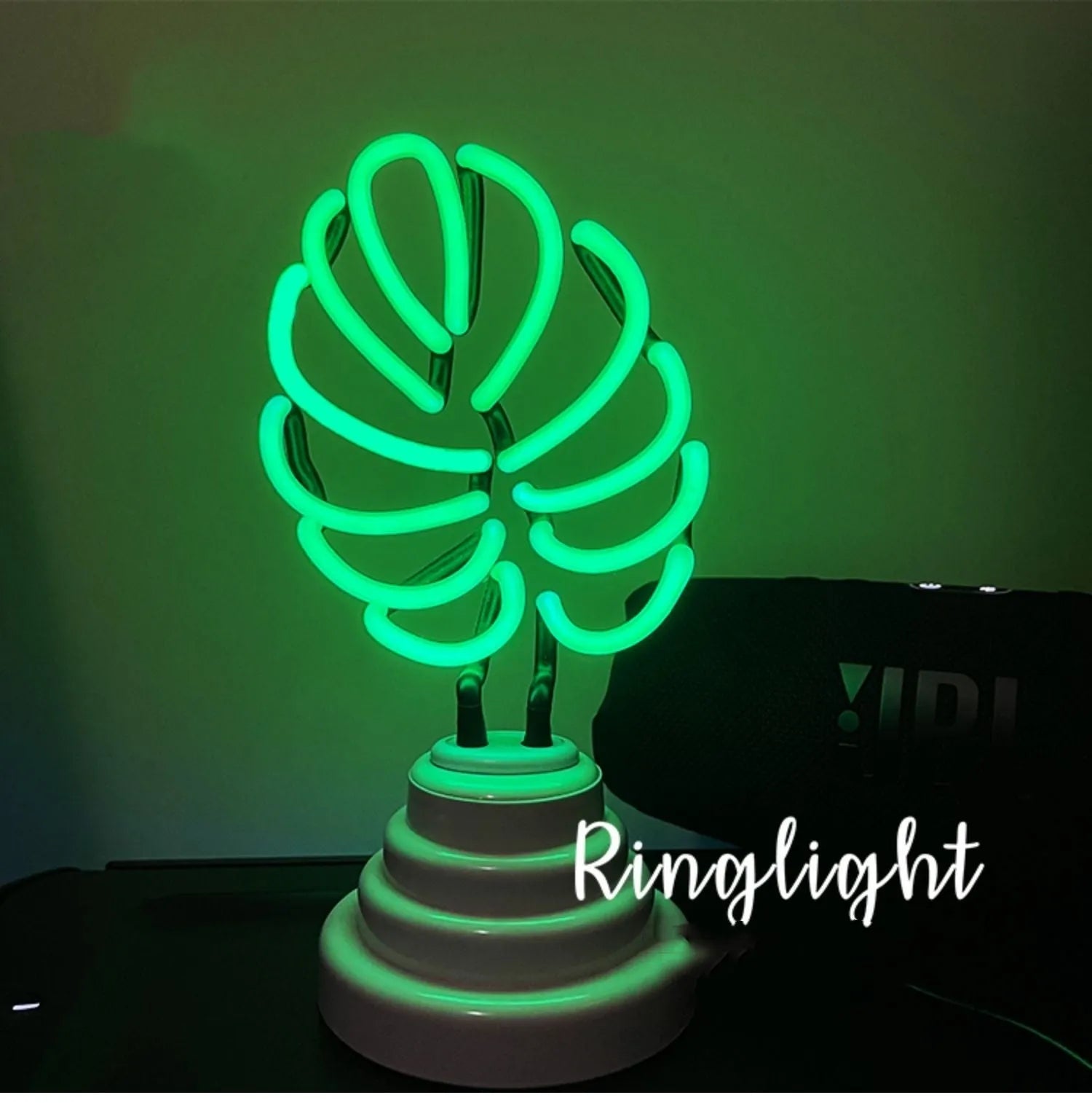 Minimalist bamboo-shaped white desk lamp with green glowing tube on a wooden table.