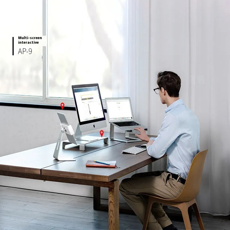 Black aluminium laptop stand with angled platform on a wooden desk