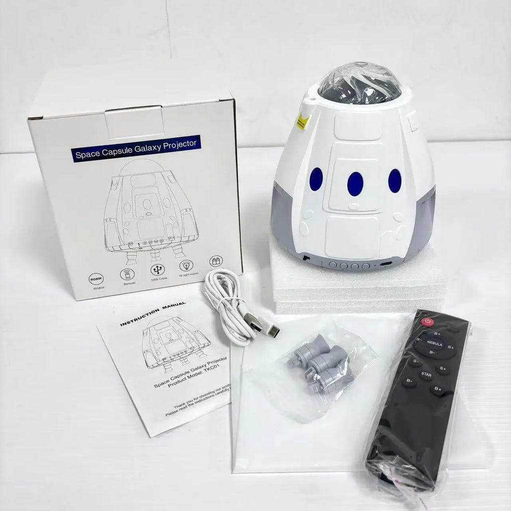 Tall white space capsule galaxy projection lamp with USB cable and remote control on a table.