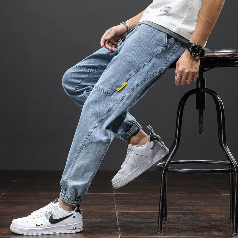 Man wearing loose straight leg cargo jeans in blue, showing mid waist and zipper fly detail.