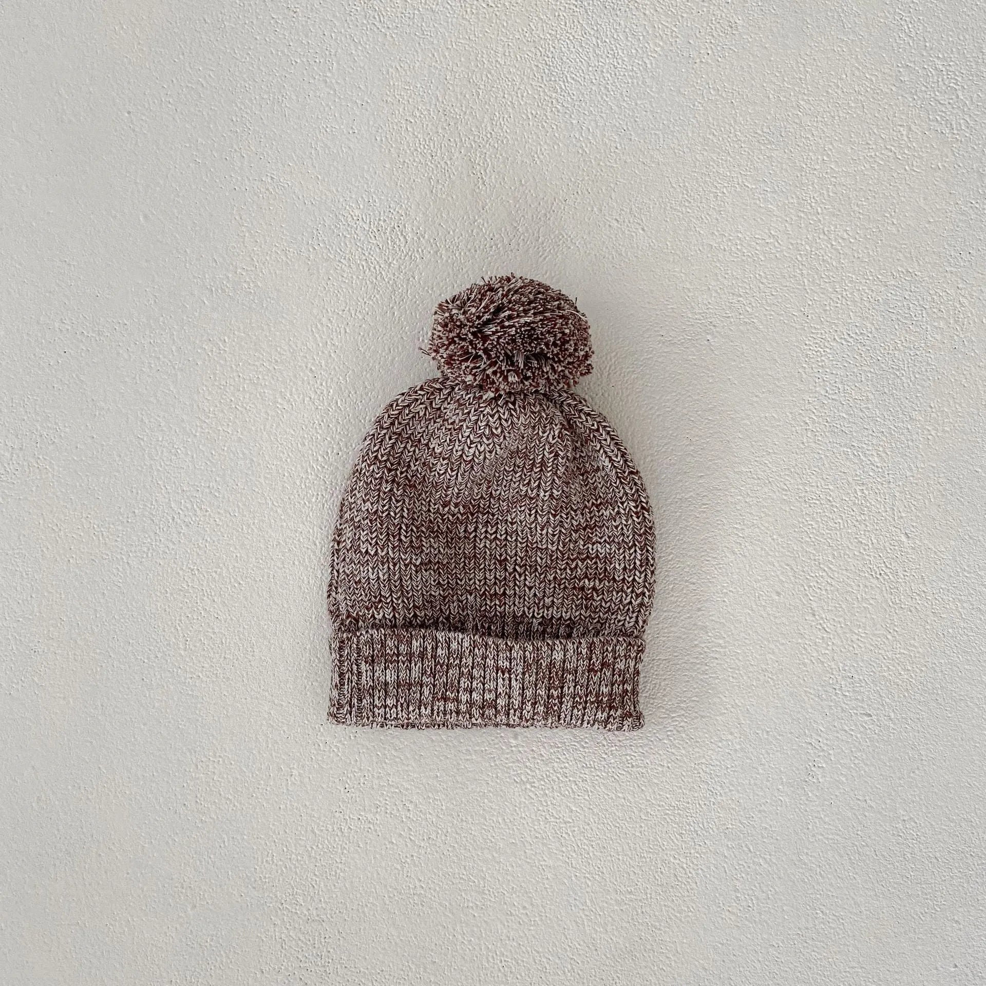 Dark brown knitted 3-piece set for infant girl with pullover blouse, pants, and fur ball hat