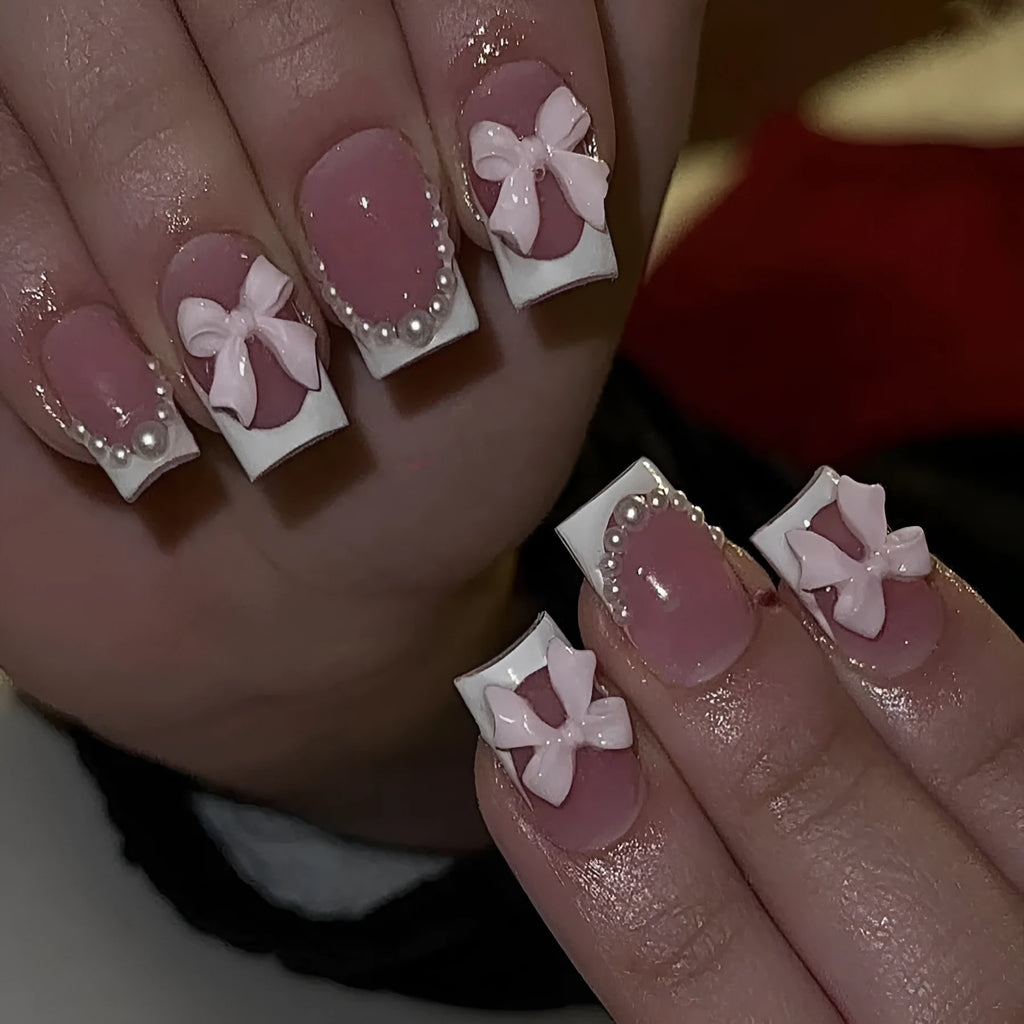 Short artificial French manicure nails with white bow, tulip, and starry sky designs on a square tip.
