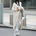 Long grey knitted women's cardigan with a hood, styled like a loose-fit trench coat.