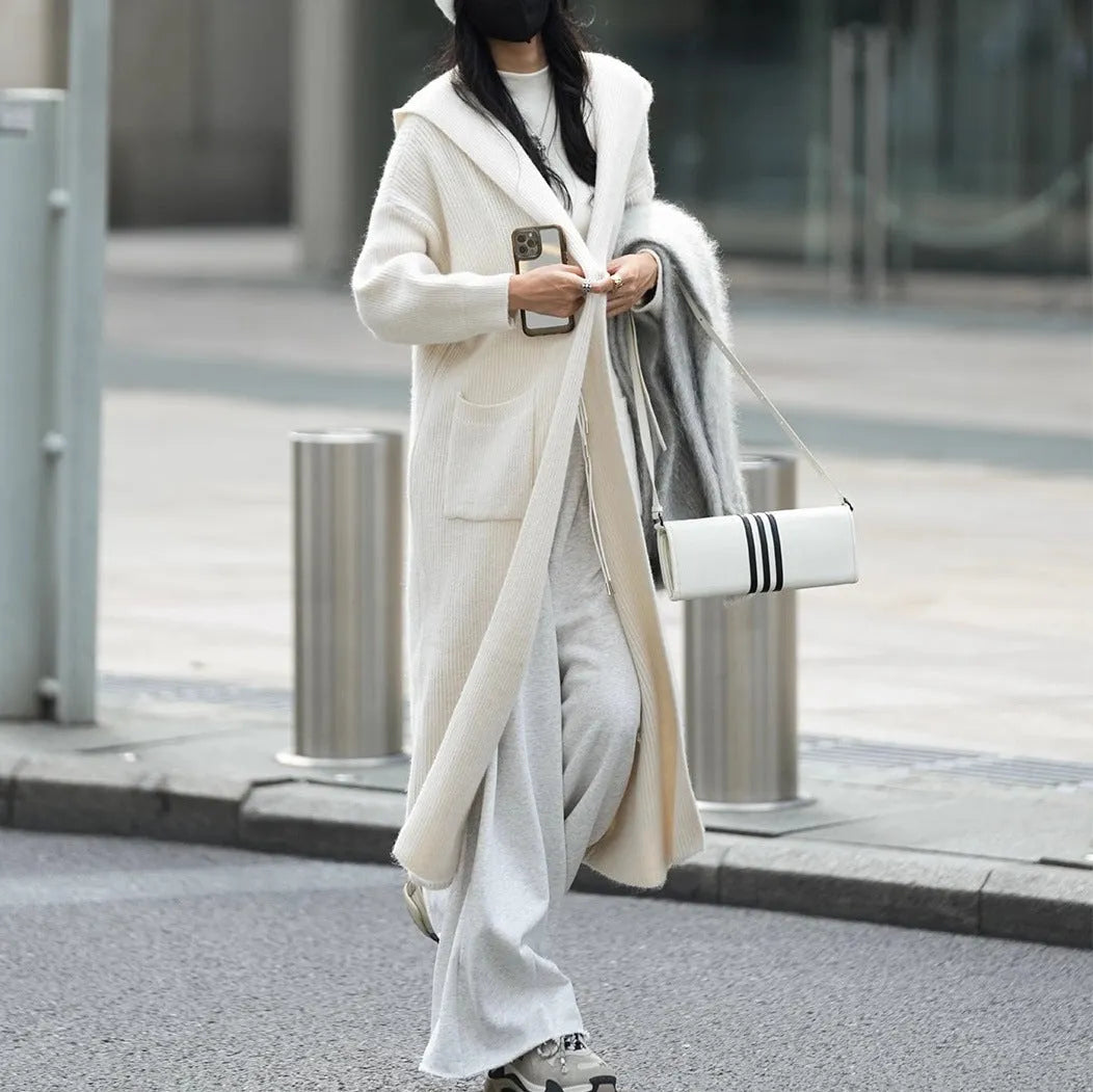 Long grey knitted women's cardigan with a hood, styled like a loose-fit trench coat.