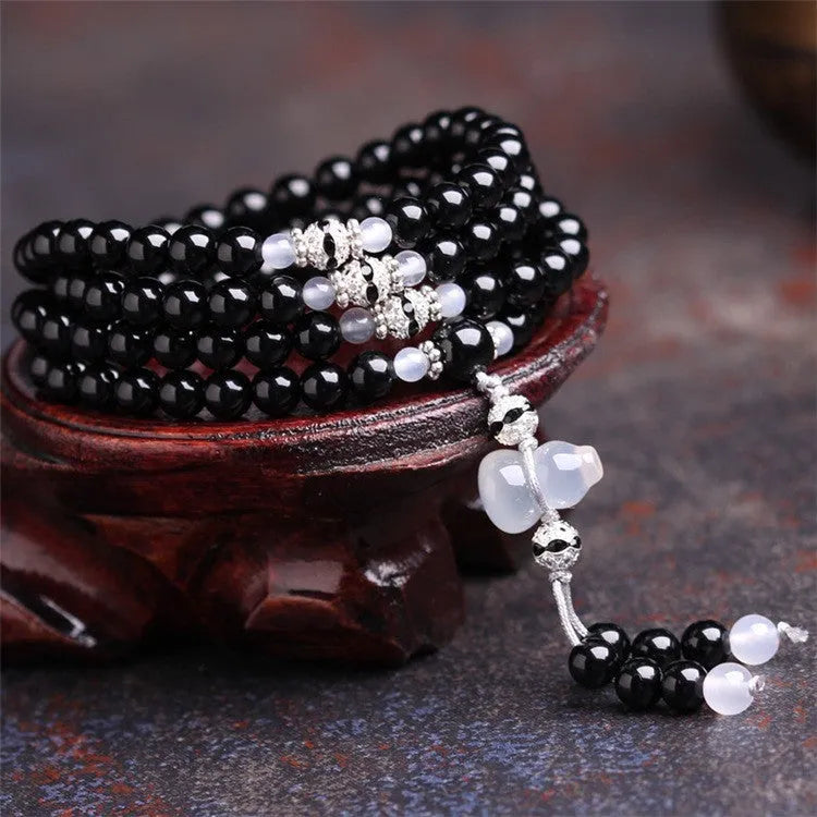 Natural black and red agate 108 bead bracelet with geometric shapes on a wrist.