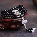 Natural black and red agate 108 bead bracelet with geometric shapes on a wrist.
