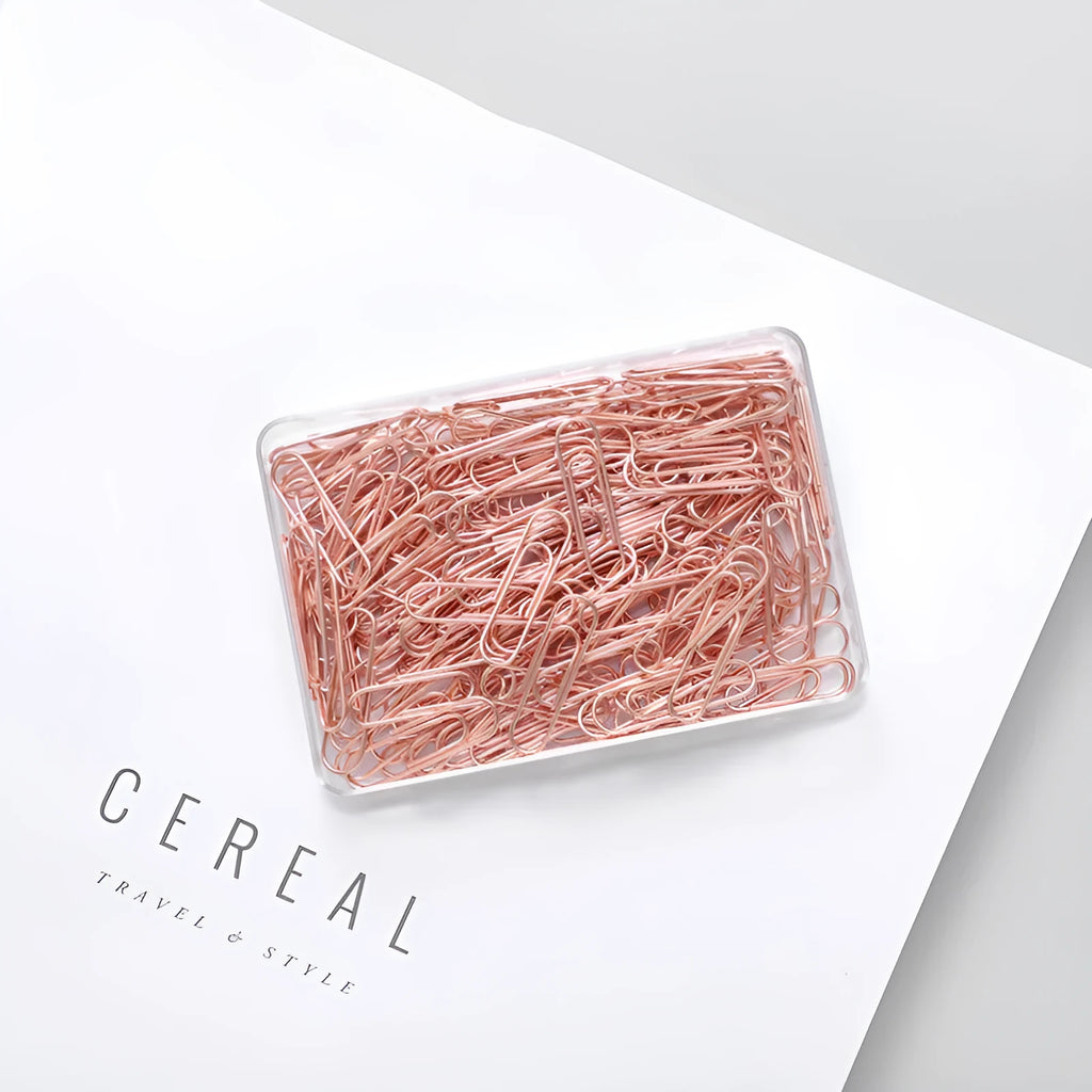 Box of 100 rose gold heart-shaped steel paper clips on a white background.