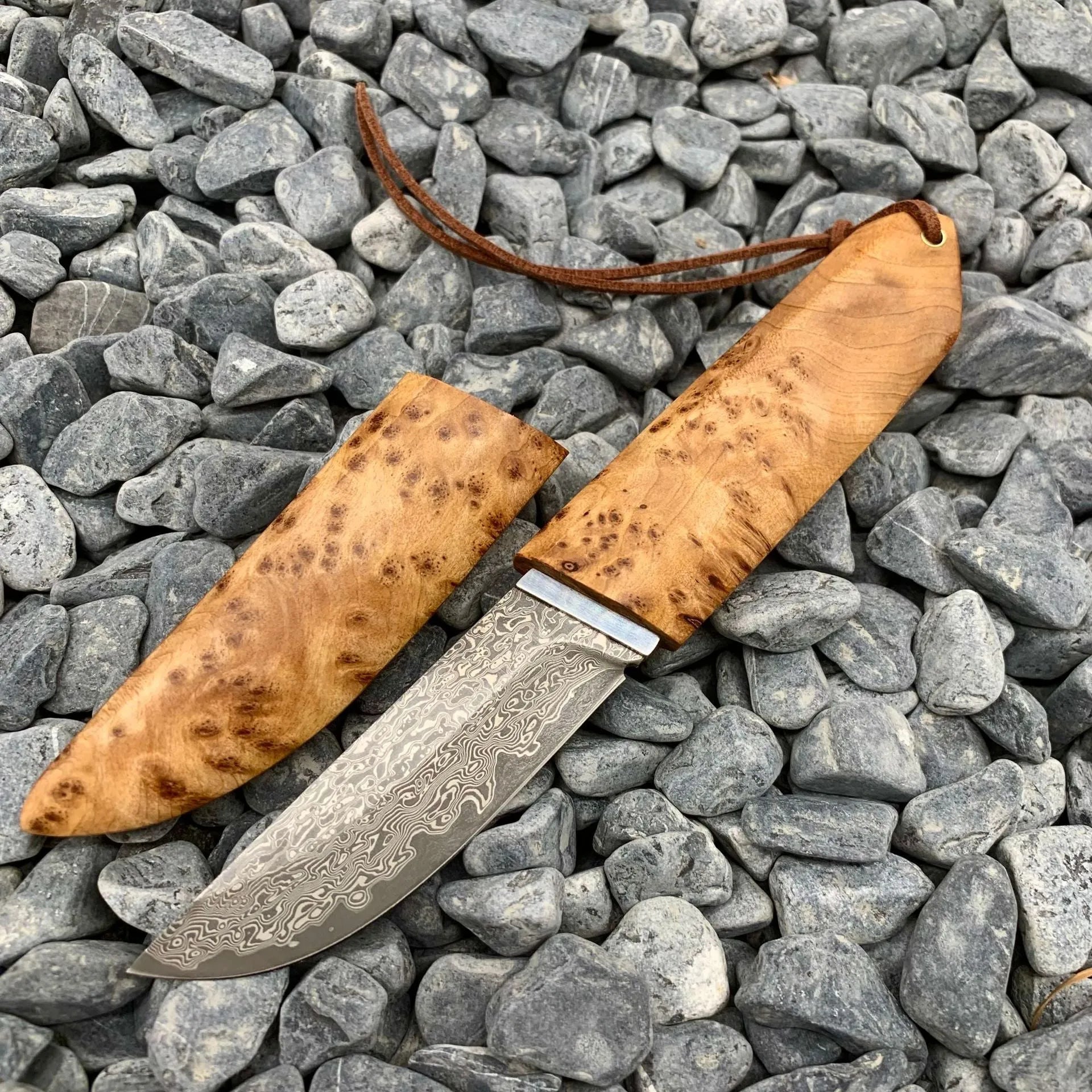 White Shadow Damascus steel short knife with Thuja wood handle, showing blade pattern.