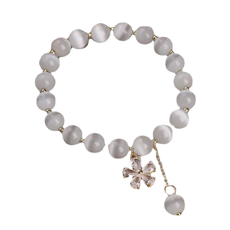 White cat's eye stone bracelet with flower tassel detailing and safety buckle closure