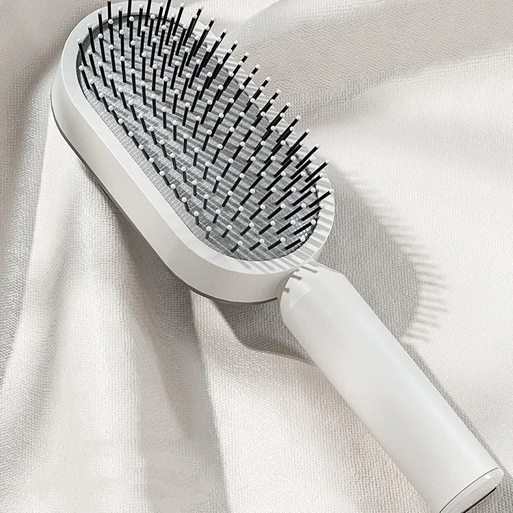 Self-cleaning hair brush with one-key button, air cushion base, and long bristles on a white background.