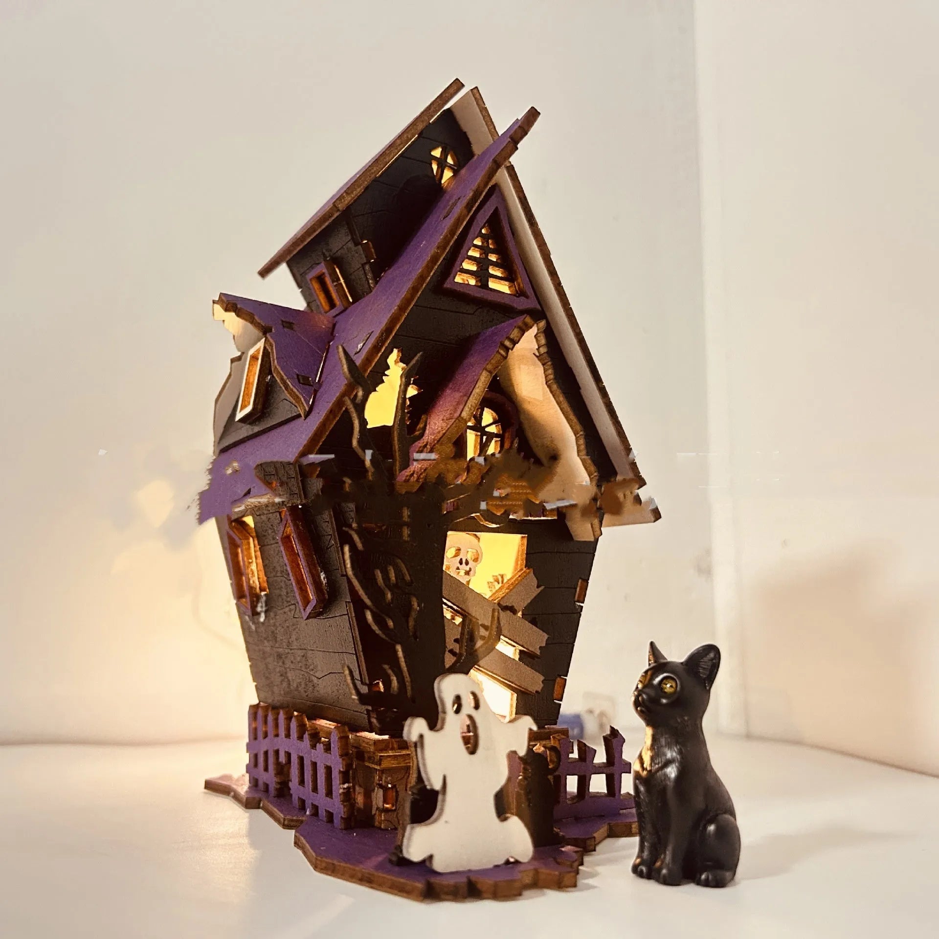 Unpainted DIY wooden haunted house Halloween decoration for use as a candlestick, shown next to a ruler for scale.