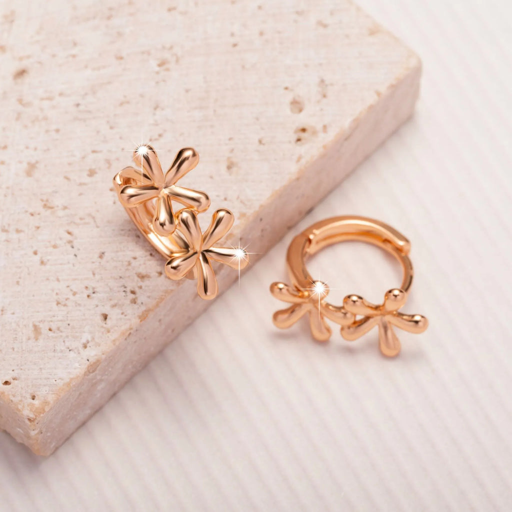 Rose gold circular earrings with a waterdrop flower design on a white background.