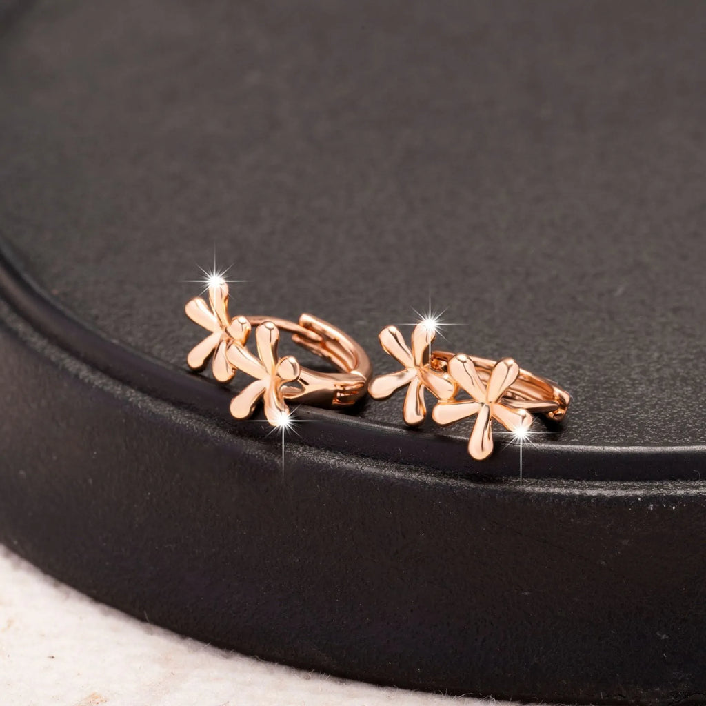 Rose gold circular earrings with a waterdrop flower design on a white background.