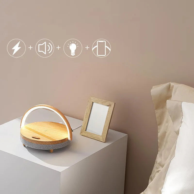 White wireless charging Bluetooth speaker and LED night light unit with phone holder on marble pattern base.