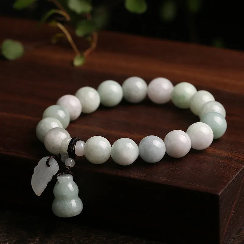 Green jade beaded bracelet with a hanging Maitreya Buddha charm on a wrist.