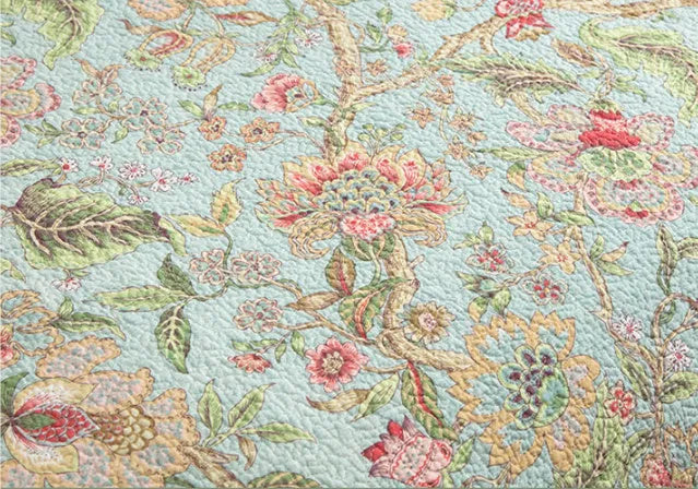 Blue American-style floral and bird quilted cotton bedspread set on a bed, showing its 230x250 cm size.