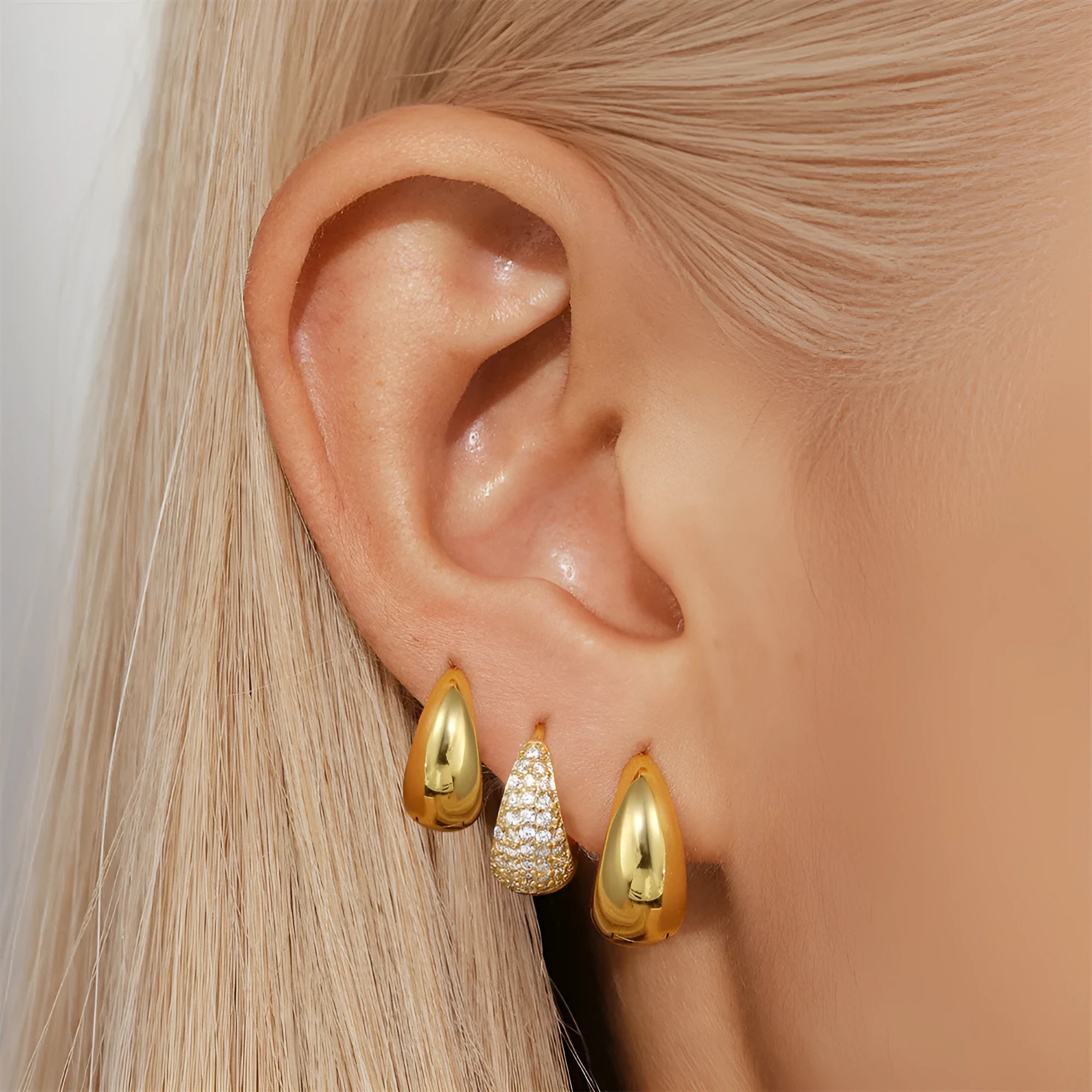 Geometric brass earclip earrings with a gold electroplated finish and round design details.