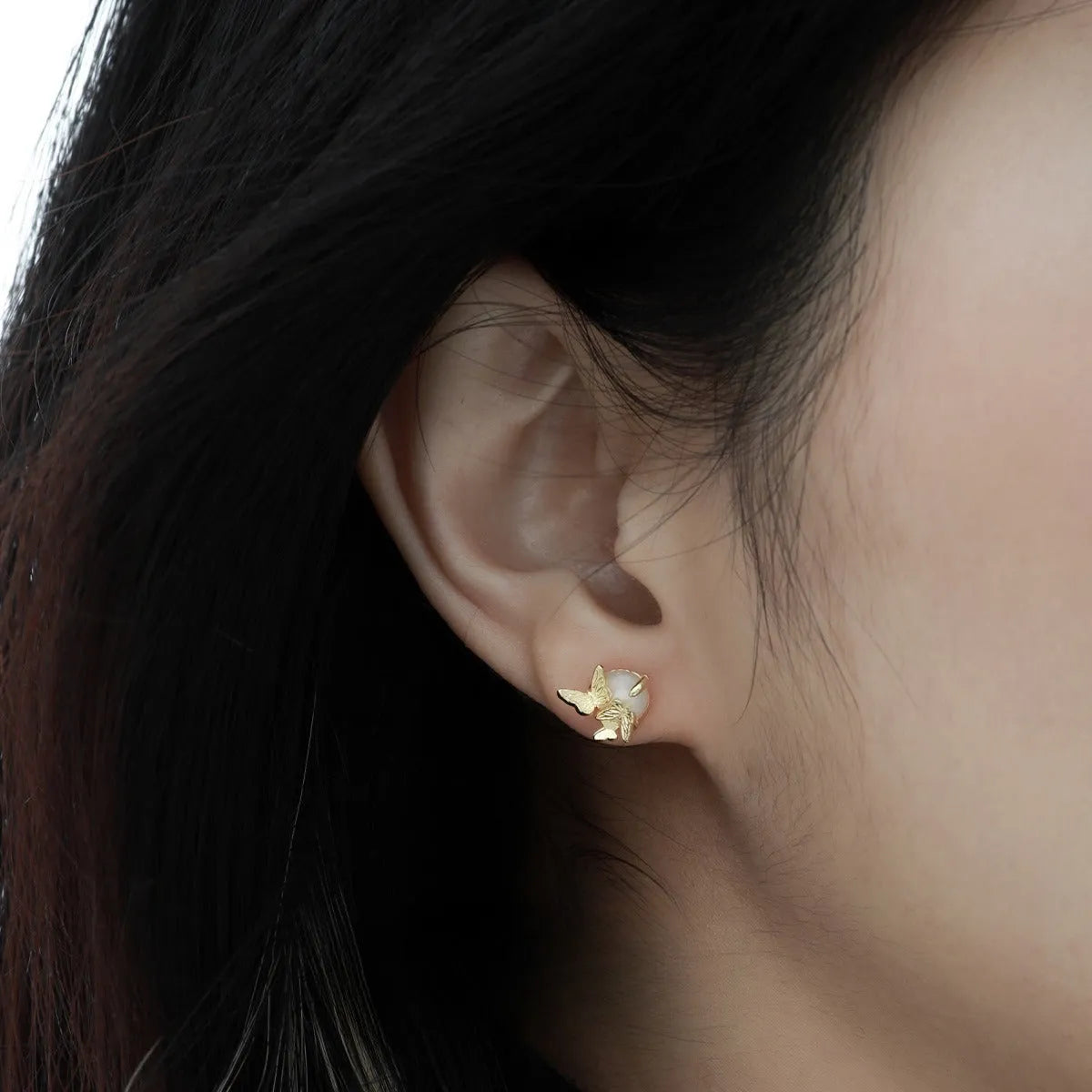 A pair of silver butterfly ear studs with animal zodiac design in gold or white gold colour.