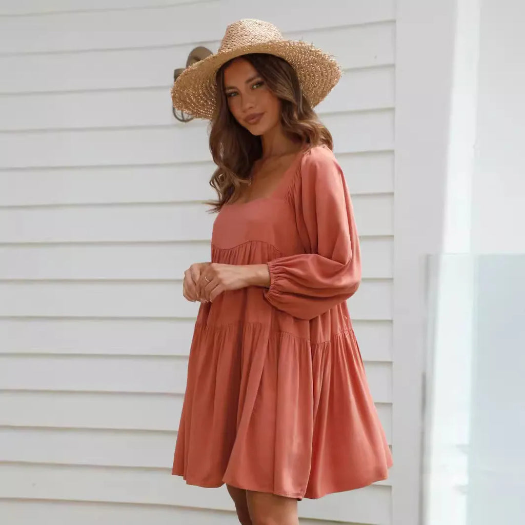 Orange backless children's dress with square collar and puff sleeves on a hanger.