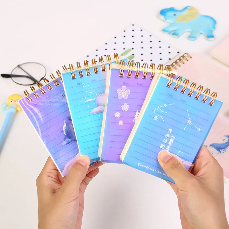 A7 rollover coil pocket notebook with decorative cover, shown with cover folded back to reveal spiral binding and inner pages.