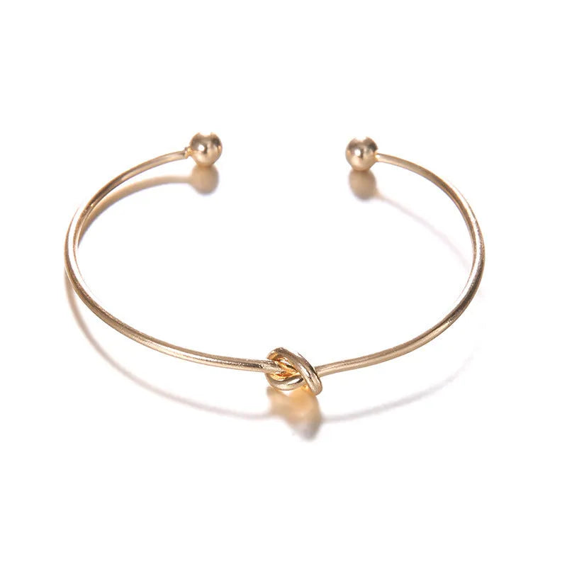 Women's gold vintage cuff bracelet with arrow and knotted design on wrist