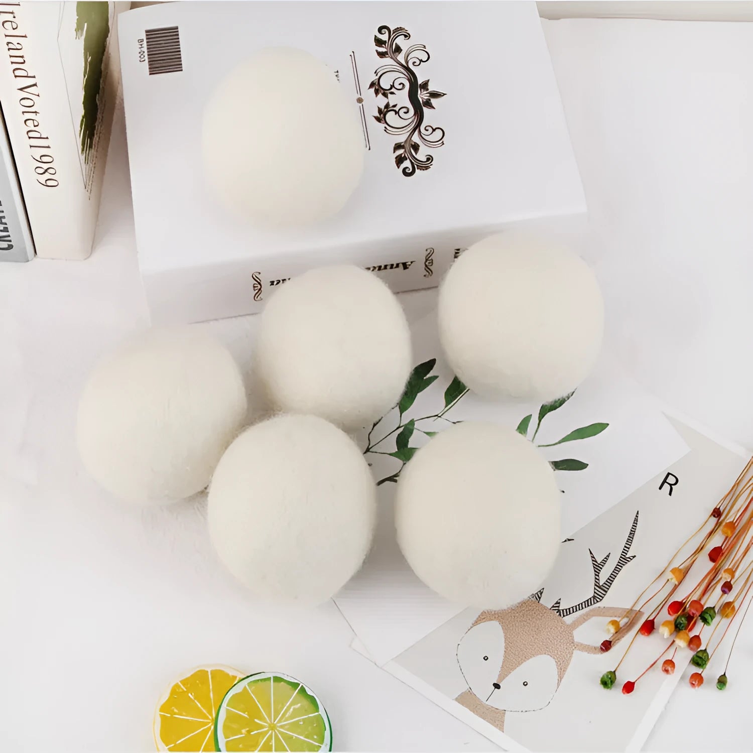 A natural wool drying ball for tumble dryers next to a plain cotton storage bag on a laundry background.