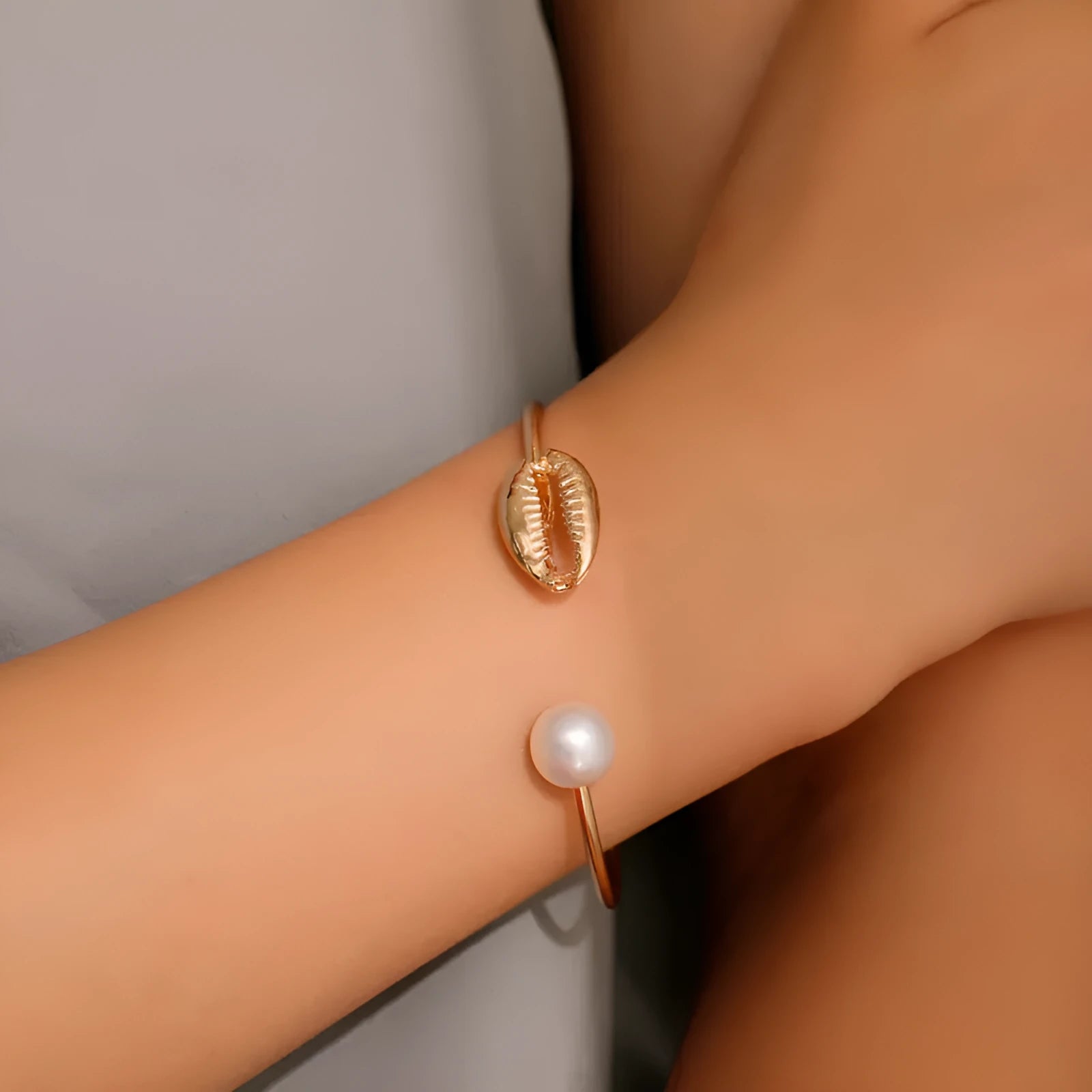 Alloy opening bracelet with pearl and shell decoration in gold finish on white background