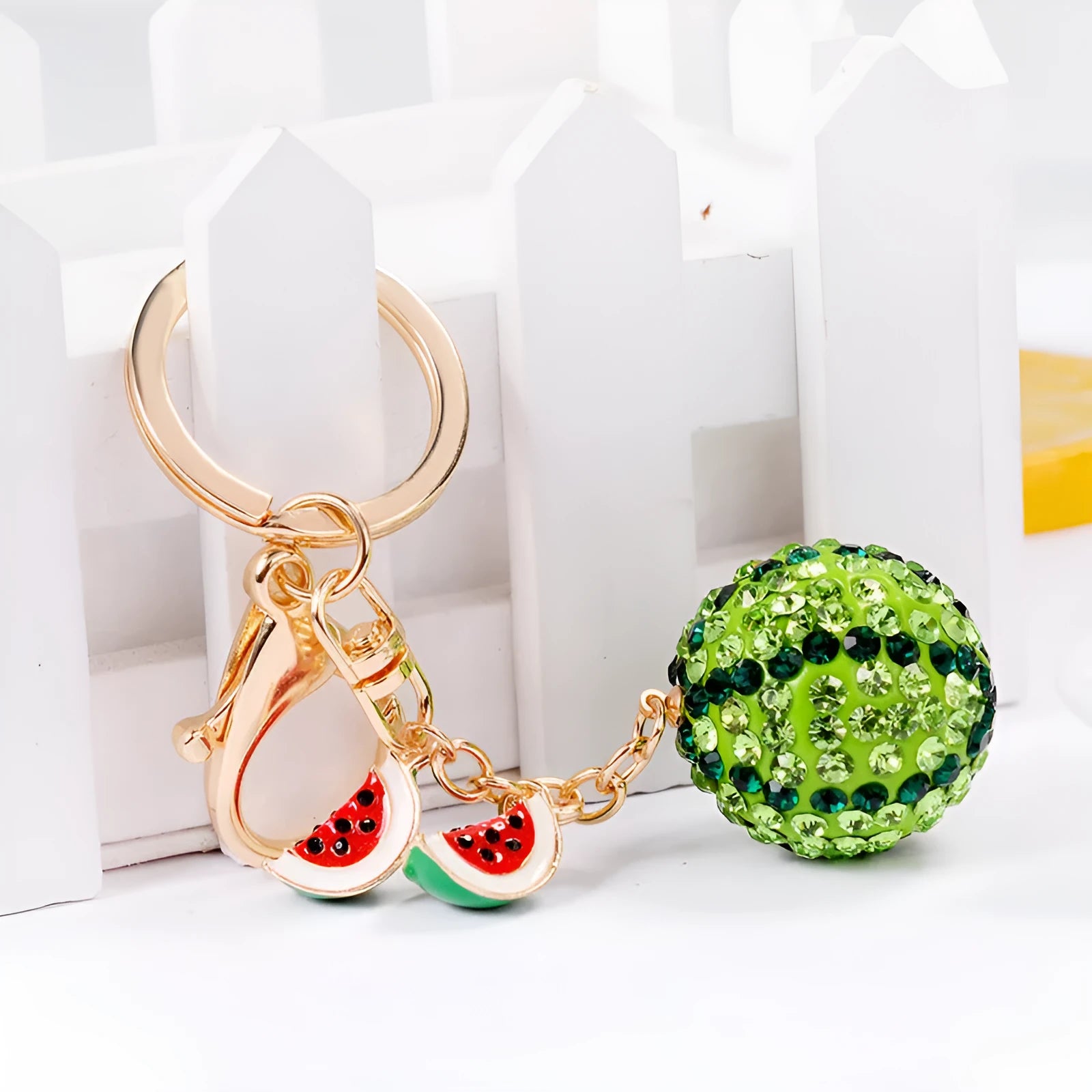Green watermelon-shaped metal keychain with sparkling crystal details on a white background.