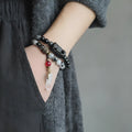 Ethnic black hair bracelet with white crystal tassel showing bending and lacing construction