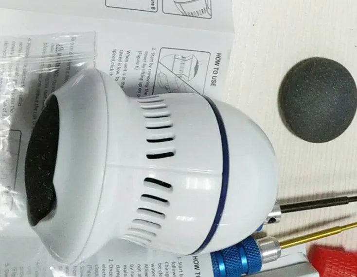 Beige and white electric foot file machine with grinding head, USB cable, two spare heads, brush, and sponge ring.