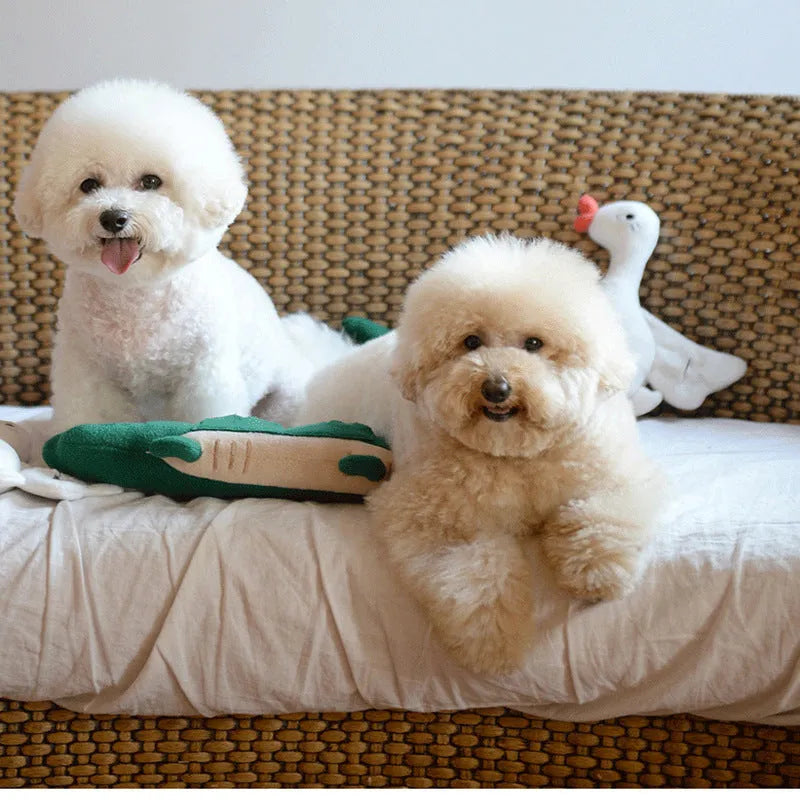 Green soft plush toy dog with floppy ears and embroidered face, lying on a white background.
