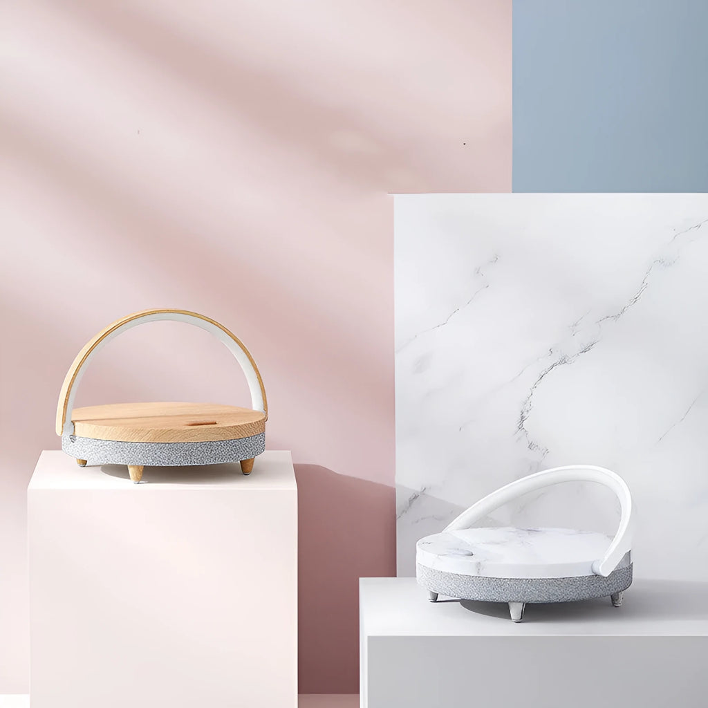 White wireless charging Bluetooth speaker and LED night light unit with phone holder on marble pattern base.