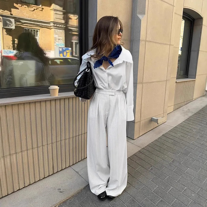 White wide-leg trousers with vertical stripes, featuring a loose casual fit and a front zipper fastening.