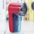 Portable electric clothing lint remover device on a white background