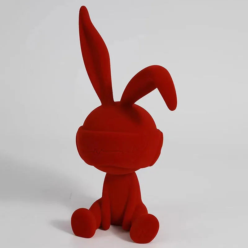 Small green resin suede blindfold rabbit table ornament on a wooden surface