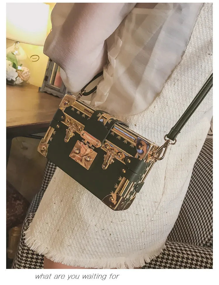 Women's hard black flap handbag with single strap, rivet details, and hasp closure.