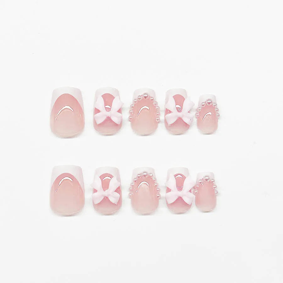 Short artificial French manicure nails with white bow, tulip, and starry sky designs on a square tip.