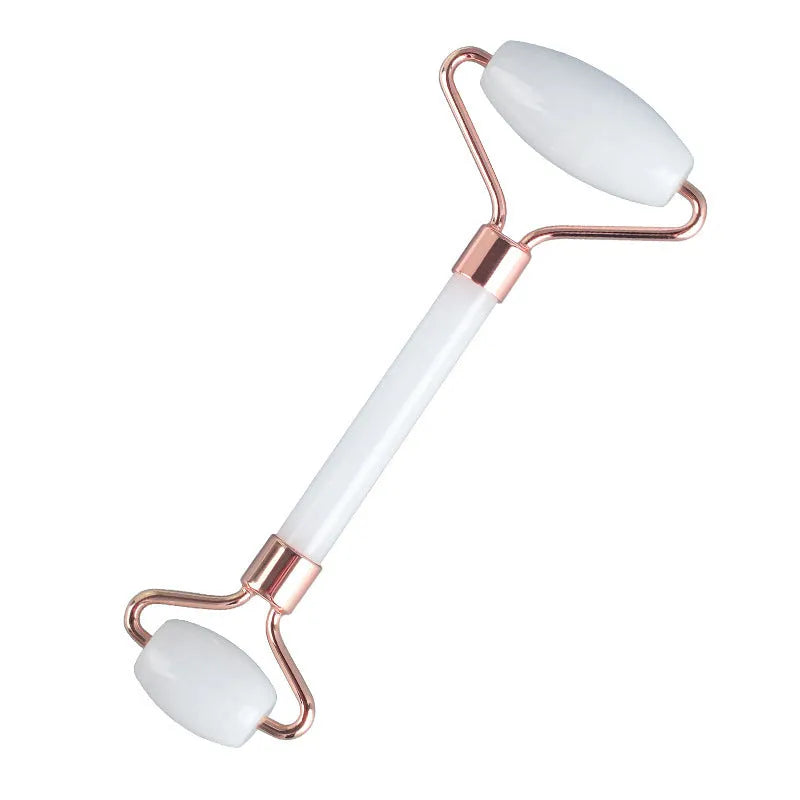 White jade double-headed facial roller and gua sha scraping tools on wooden storage board
