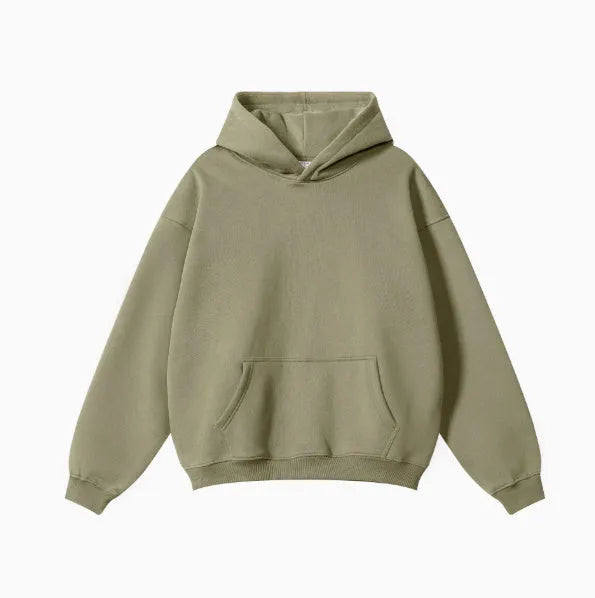 A man wearing a loose grey hooded cotton terry sweater with drop-shoulder sleeves.