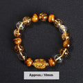 Close-up of a yellow tiger's eye and citrine bead bracelet with a geometric pi xiu charm on a wrist.